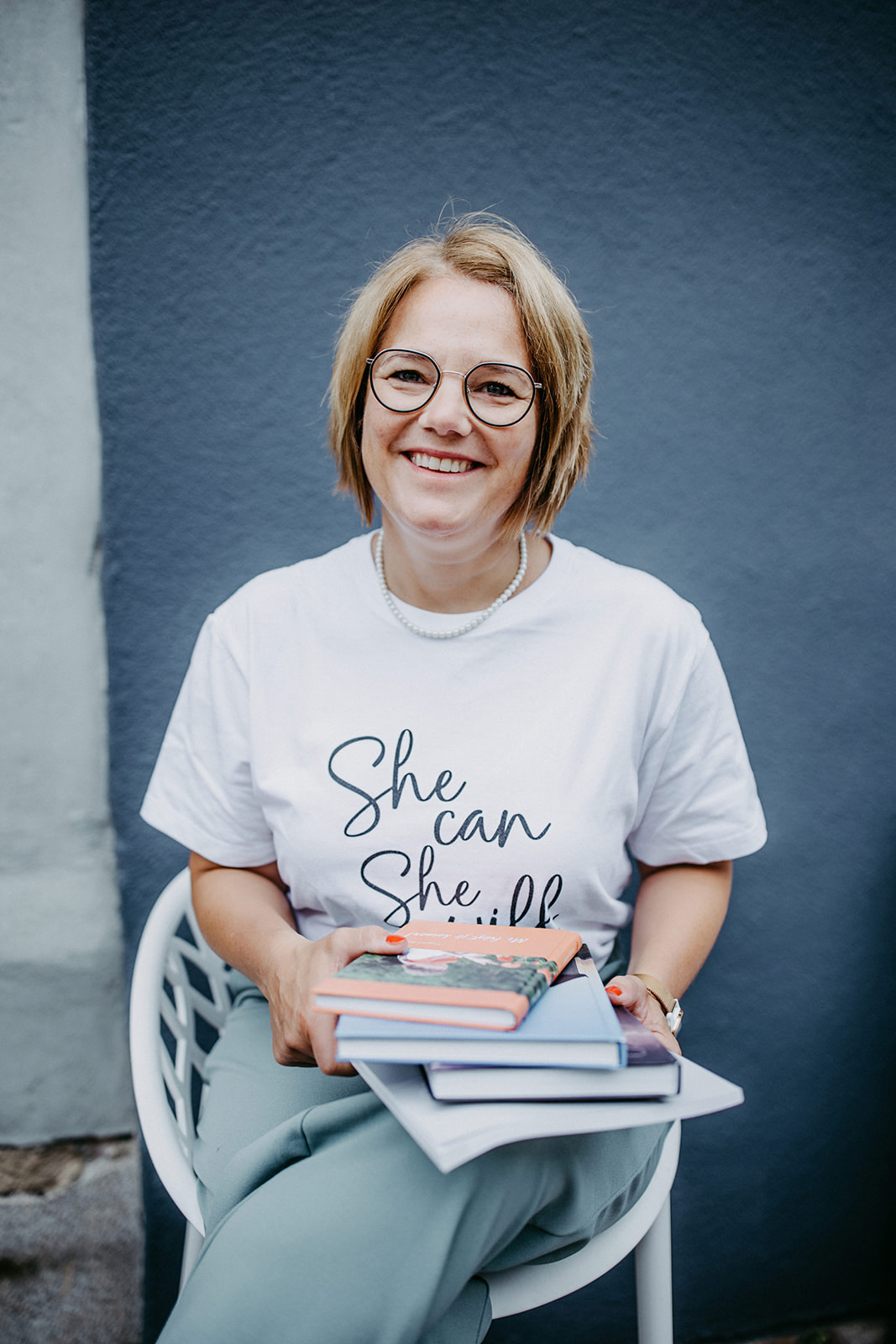 Frau hält selbst designetes Buch in der Hand und schaut in die Kamera